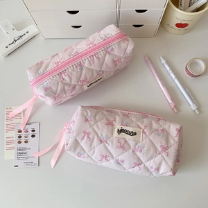 Detailed close-up of quilted floral pencil bags with pink bow embroidery and ribbon zippers