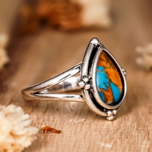 Détail macro d'une bague goutte vintage avec textures de pierre turquoise et orange