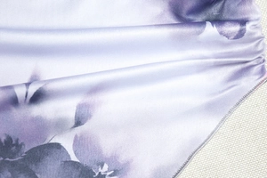 Vue détaillée du tissu à imprimé floral tie-dye violet avec une texture satinée