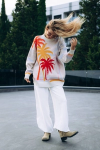 Outdoor street style shot of a loose knit sweater featuring colorful palm tree patterns