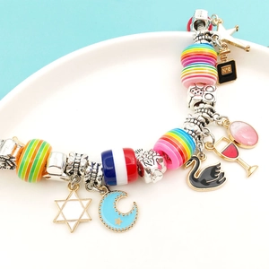 Pandora style bracelet with rainbow striped resin beads and mixed charms on a white plate