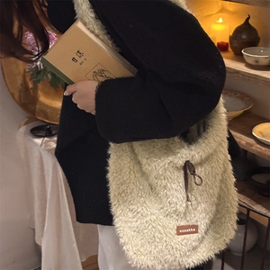 Close-up of beige fuzzy lamb-wool tote bag featuring a brand tag and drawstring detail