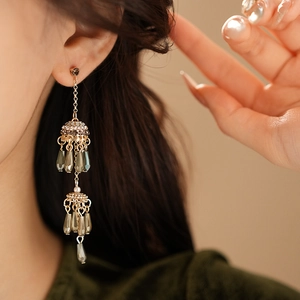 Close-up of vintage gold tassel earrings with crystals and pearls worn by a model