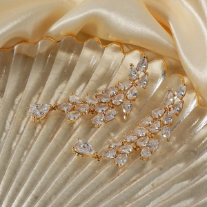 Detailed view of gold branch-style drop earrings with zircon tassels on silk fabric