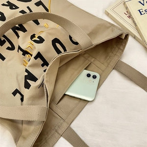 Detail view of khaki canvas tote bag interior showing functional phone storage pocket