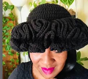 Detailed view of hand-crocheted black knit hat with sculptural ruffled edge design