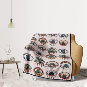 Detailed view of bohemian eye patterned flannel blanket draped on a cozy yellow sofa armchair
