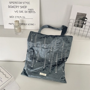 Detailed view of navy blue velvet tote bag featuring pearl accents and brand tag