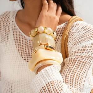 Bohemian milk white resin cuff bracelets with gold accents on model wrist in resort style