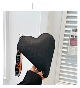 Détail du sac à main cœur noir avec texture litchi et bandoulière brodée LOVE
