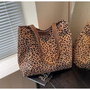 Détail du sac cabas en toile léopard avec des anses en cuir marron et finitions