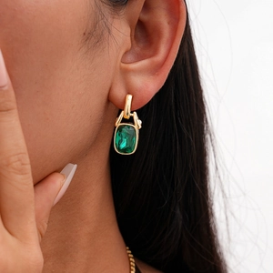 Dettaglio di orecchini a pendente verde smeraldo con finiture in metallo dorato
