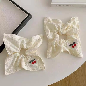 Two-pack white lace scrunchies featuring delicate red cherry embroidery in a flat lay view