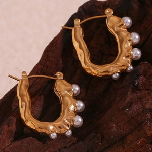 Close-up of 18K gold plated U-shape earrings with lava texture and inlaid pearls