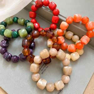 Gros plan de bracelets en perles acryliques colorées avec formes carrées et texture marbrée