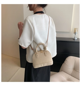 Beige faux crocodile skin shell bag with gold hardware worn as a crossbody purse
