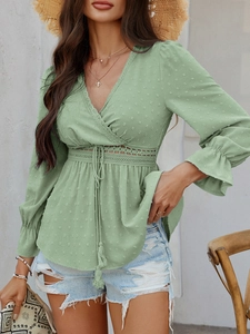 Détail de la blouse verte à col en V avec texture à pois, dentelle et ceinture nouée