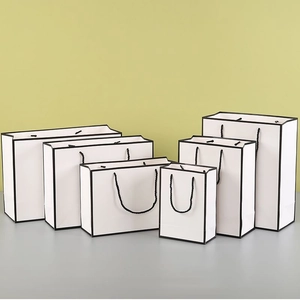 Detail view of six white paper gift bags in various sizes with black rope handles