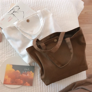 Close-up of small canvas tote bags with metal snap buttons in white and brown