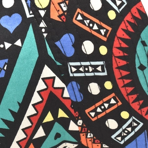 Close-up of geometric pattern and blue hearts on multi-colored fabric of the bucket hat
