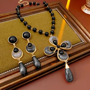 Detailed view of vintage gold flower and water drop jewelry set with black gemstones