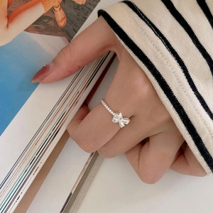 Detail of silver bow ring with beaded band worn against a cozy lifestyle background