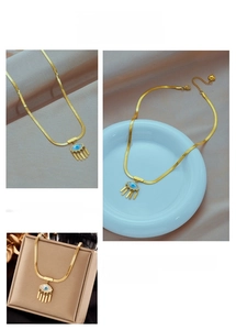 Detail of 18K gold snake chain necklace featuring blue evil eye pendant and tassels