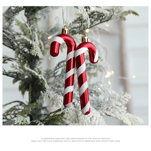 Close-up of red and white striped candy cane Christmas ornaments on a snow-covered pine branch