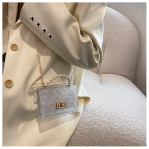 Detail of transparent PVC jelly bag featuring pearl handle and gold chain strap