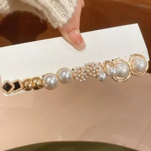 Detail of French luxury gold hair clip with pearls and black diamond accents