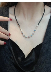 Close-up of rainbow stone dice pendant with colorful gems on silver chain necklace