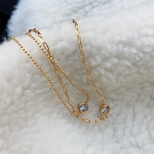 Close-up of a double-layered 18k gold plated bracelet with sparkling zircon charms