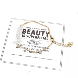 Macro shot of gold-plated chain bracelet with natural irregular crystal stones on card