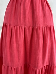 Close-up detail of tiered rose red cotton linen dress showing fabric texture and pleats