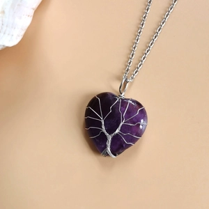Close-up of heart-shaped purple stone pendant with silver wire-wrapped tree of life design