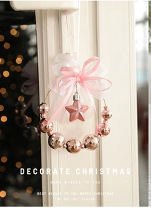 Dettaglio di ghirlanda natalizia rosa con fiocco doppio e decorazioni festive lucide