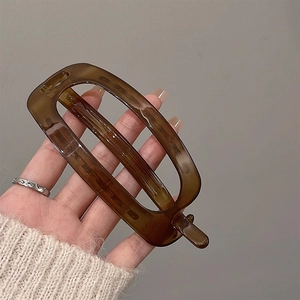 Barrette à cheveux rectangulaire marron minimaliste tenue en main pour la taille