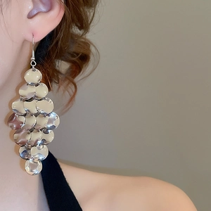 Macro shot of layered silver metal sequins on long drop earrings for a trendy look