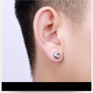 Close-up of a silver stainless steel round stud earring with a clear crystal on an ear.