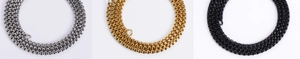 Detailed view of three box chains in silver, gold, and black finishes on a plain surface