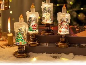 Detail of Christmas water globe candle lamps with festive figurines and bronze bases