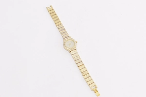 Close-up of golden women's watch with brilliant rhinestones on dial and metal band