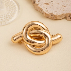 Close-up of a minimalist gold knotted metal hair tie showcasing its glossy mirror finish