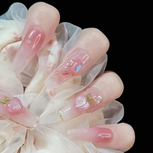 Detailed macro view of 3D peach press-on nails with pink gradient and pearl accents