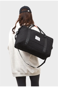 Close-up of quilted black fitness bag with adjustable strap and woven brand label