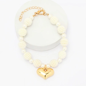 Elegant pet pearl necklace featuring a large gold heart pendant on a white round display