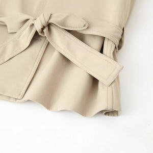 Fashionable beige trench coat for women with a belted waist tied in a bow