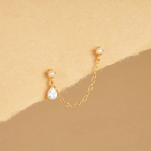 Macro detail of S925 silver gold-plated chain earring with pear-cut zircon and pearls