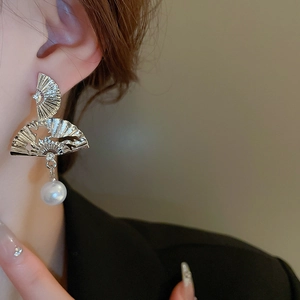 Détail d'une boucle d'oreille éventail en argent avec perle portée par un mannequin