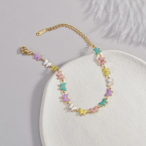 18K gold plated stainless steel bracelet with colorful enamel butterfly charms on a white tray